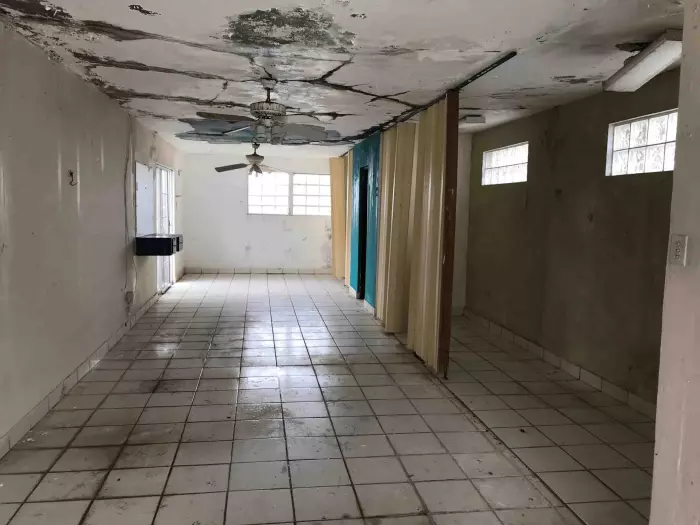 Sala vacía con techo dañado por filtraciones de agua, ejemplo de casa que compramos tal como está