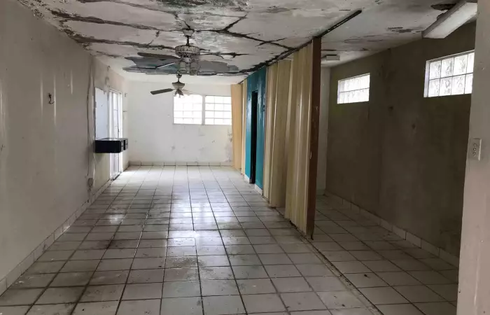 Sala vacía con techo dañado por filtraciones de agua, ejemplo de casa que compramos tal como está