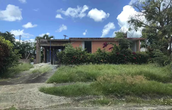 Casa con patio de hierba crecida y estructura en obra en Puerto Rico, propiedad en cualquier condición