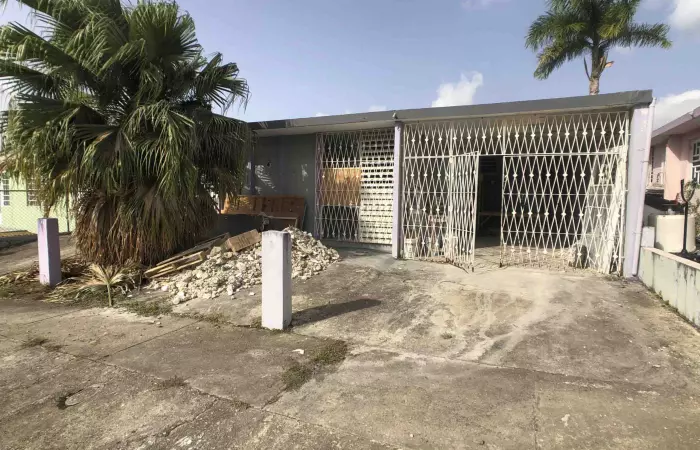 Casa con portones de seguridad y escombros en la marquesina en Puerto Rico