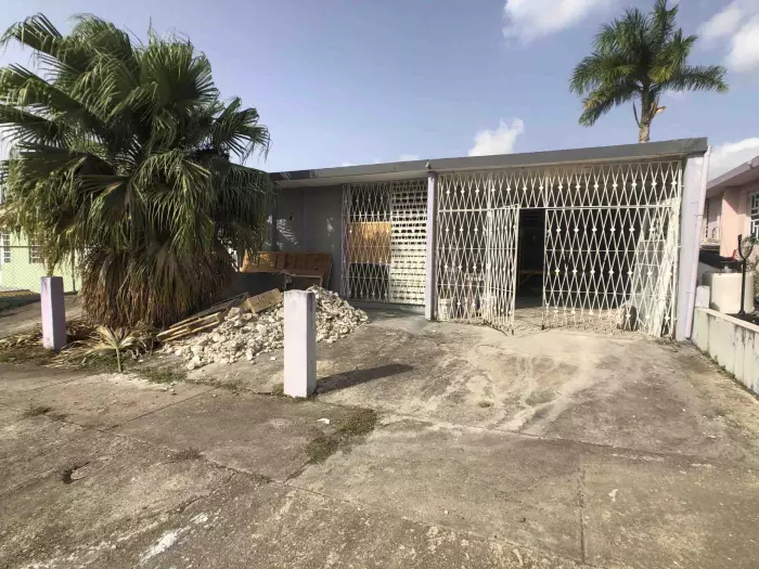 Casa con portones de seguridad y escombros en la marquesina en Puerto Rico