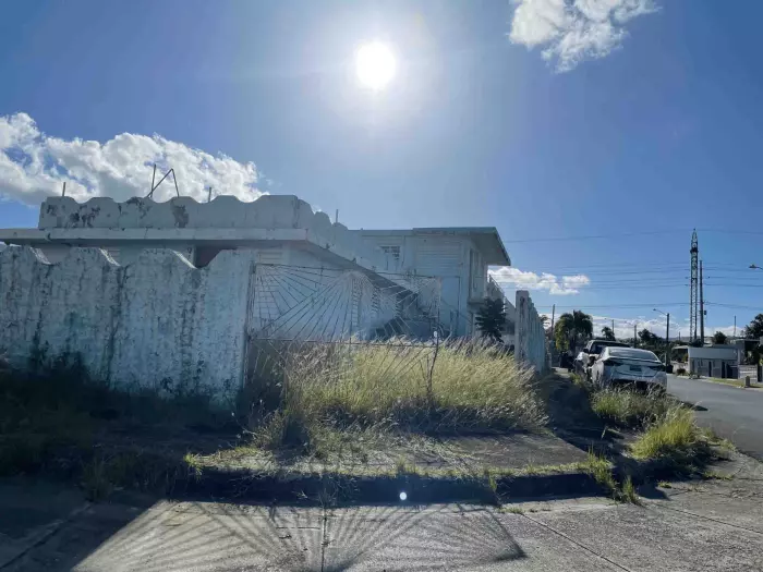 Casa de dos plantas con verja ornamental y patio desatendido en Puerto Rico
